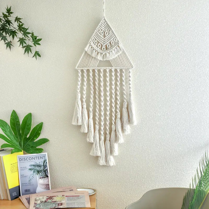 A cream-colored handwoven home decor triangle dream catcher tassels wall hanging featuring intricate knotwork and dangling tassels.