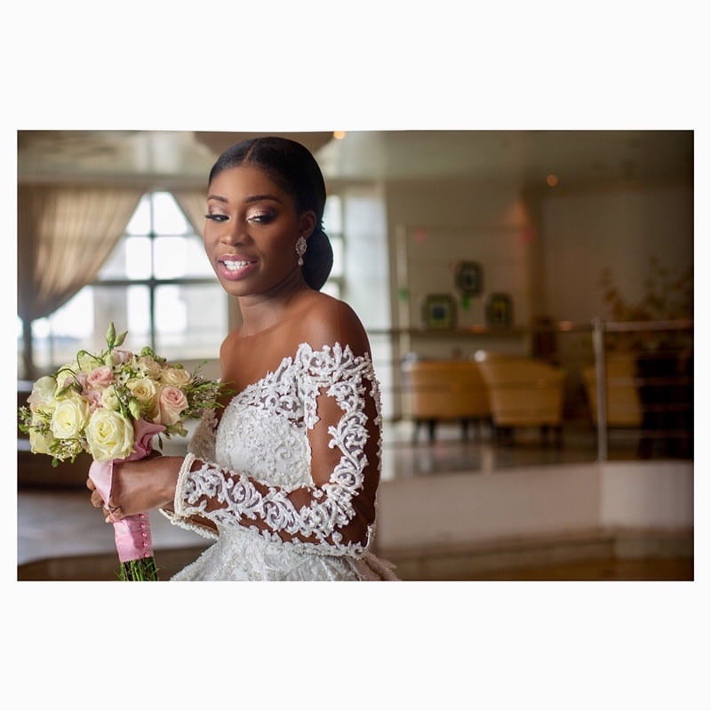 Elegant off-the-shoulder white lace custom wedding gown featuring intricate floral detailing and long sheer sleeves for bridal dresses.