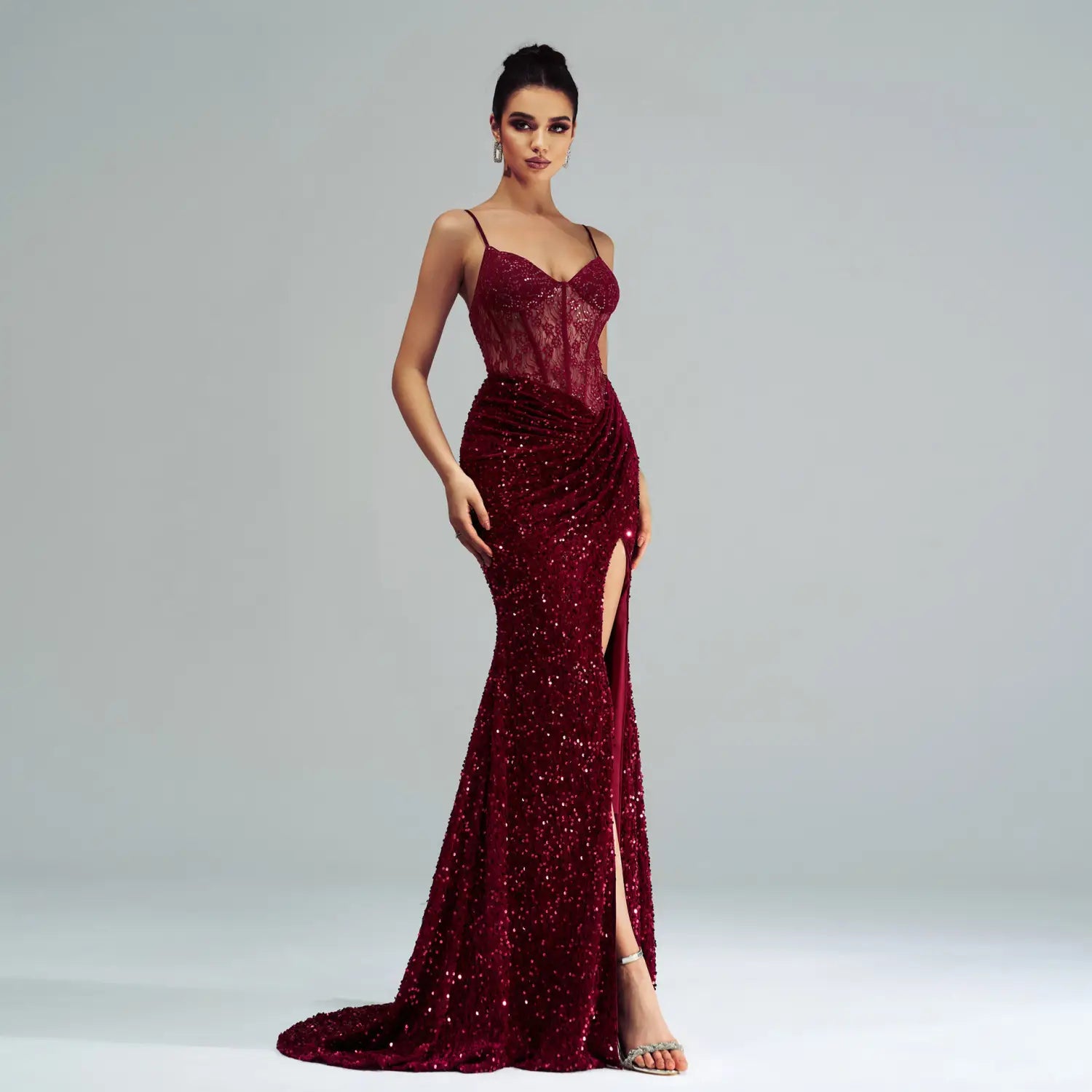 A burgundy sleeveless sequined high slit evening dress featuring a lace bodice and shimmering mermaid silhouette.