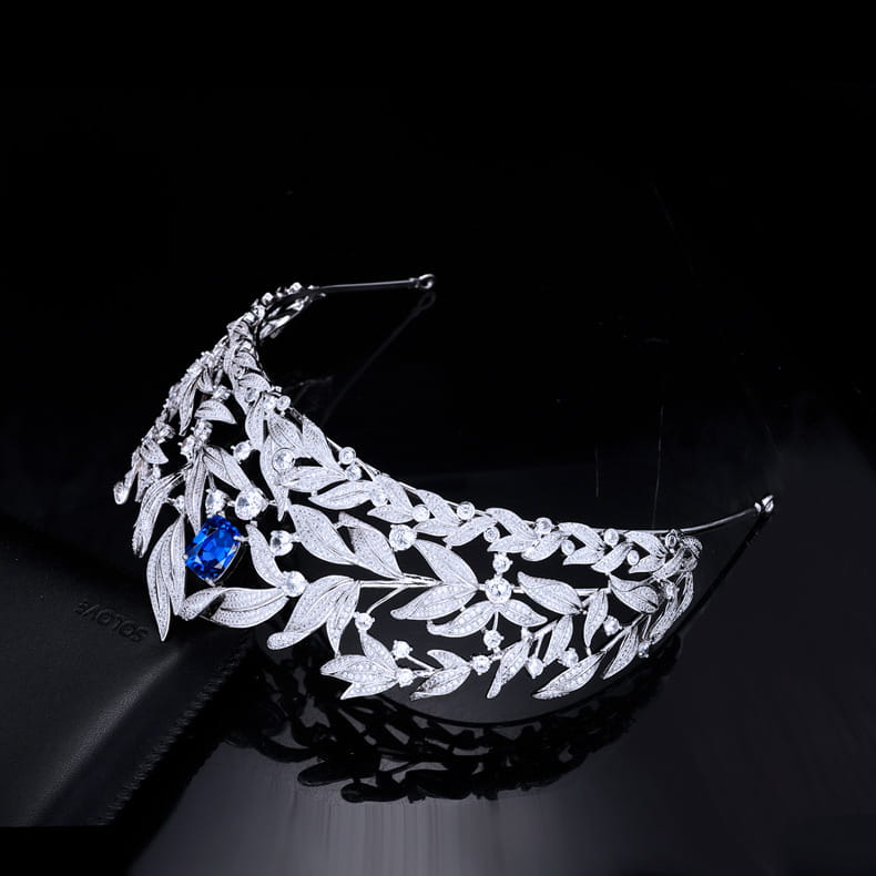 A sparkling silver tiara with intricate leaf patterns and a central blue gemstone featuring sapphire crown copper micro inlay zircon details.
