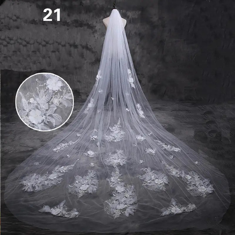 a delicate floor-length white lace wedding veil with intricate floral appliqués and butterfly motifs designed in a meters wide style
