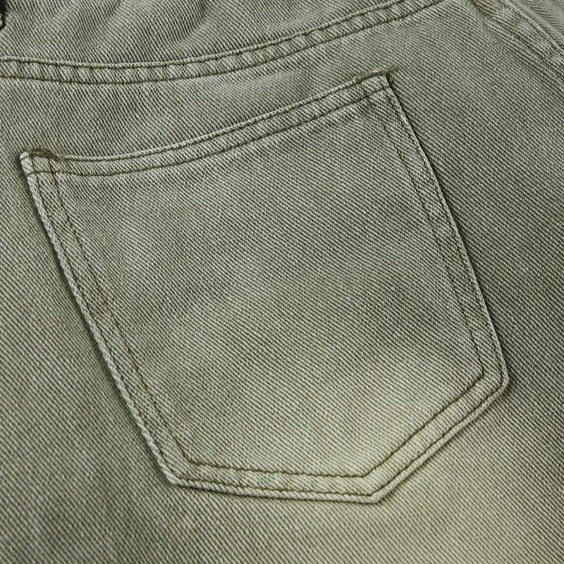 A close-up of the back side of light green jeans double belt adjustable buckle shorts showing faded olive green denim with visible stitching and subtle texture.