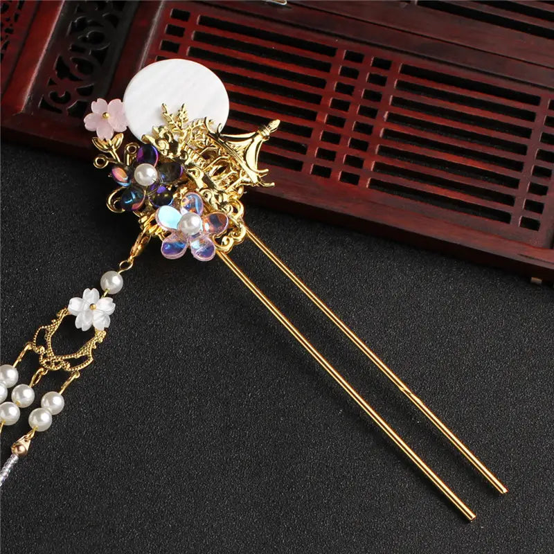 Elegant gold ancient costume hairpin adorned with a white circular disc, iridescent gemstones, delicate pink and clear flower charms, and hairpin accessories tassel with dangling pearl beads.