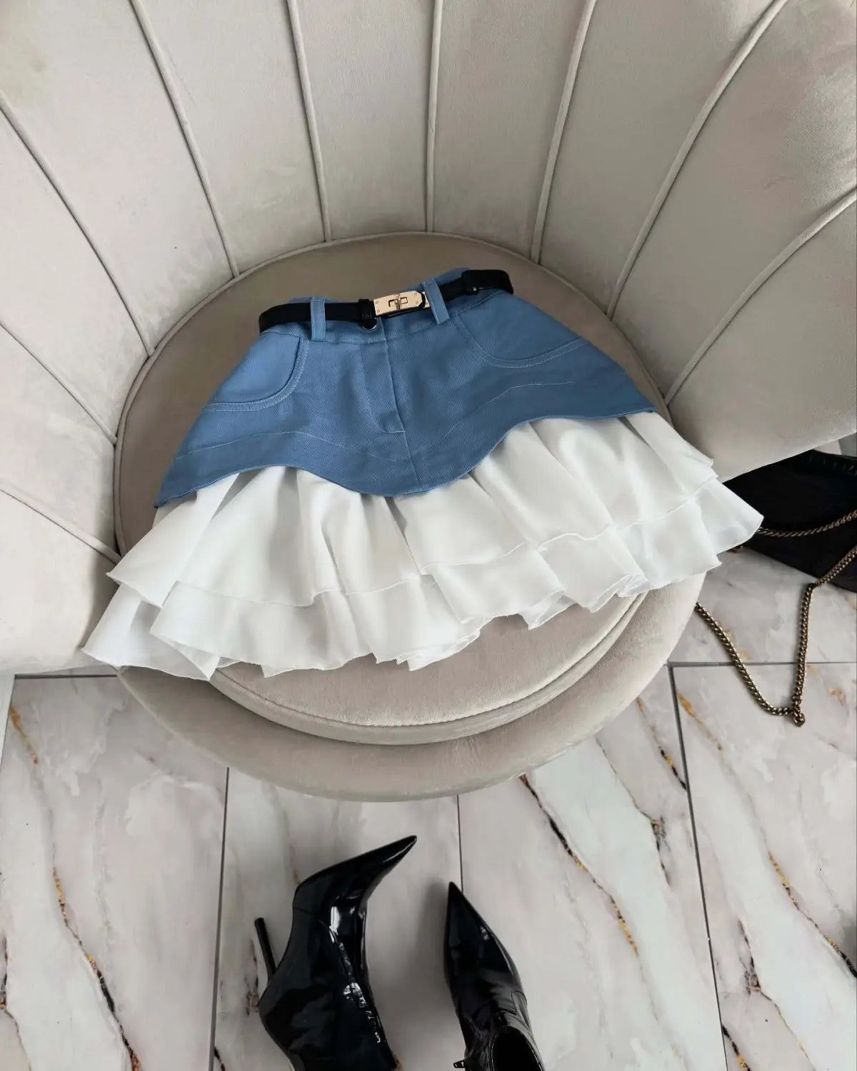 Beige two tone ruffled high waist tiered skirt featuring a blue denim top layer, white ruffled bottom, and a black belt with gold tone buckle.