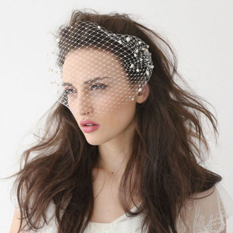 A delicate white bridal veil pearl hair comb features a lace-like mesh with large hole design and pearl embellishments.