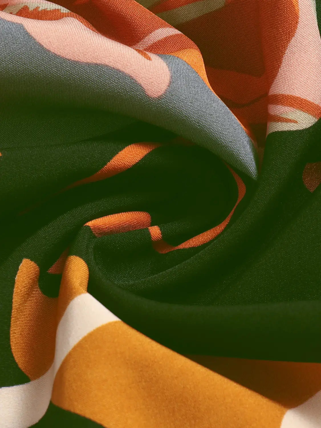 a cream tiered pleated floral print skirt paired with a vibrant flowing scarf featuring a bold abstract pattern in shades of orange teal and white against a deep green background with a floral print elastic waist.