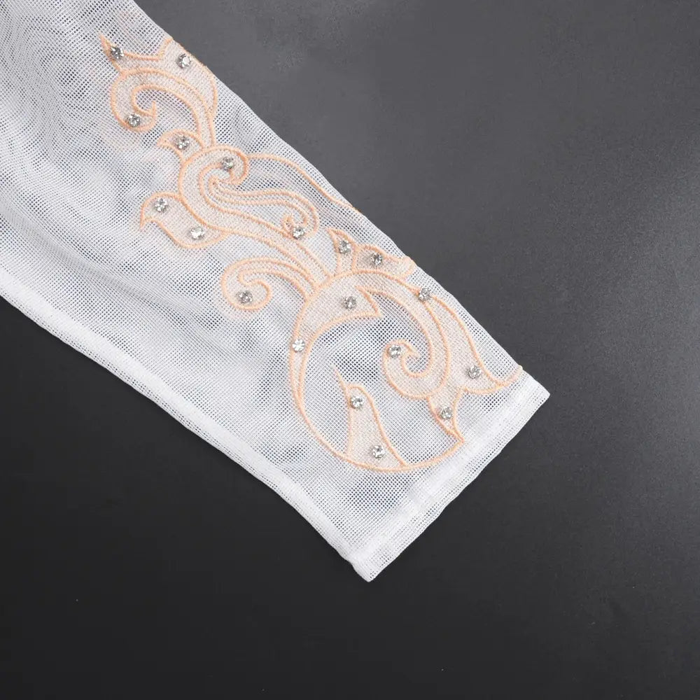 white sheer mesh arm sleeve with delicate peach-colored embroidered swirls and sparkling rhinestones paired with luxury rhinestone beaded black peplum formal dress