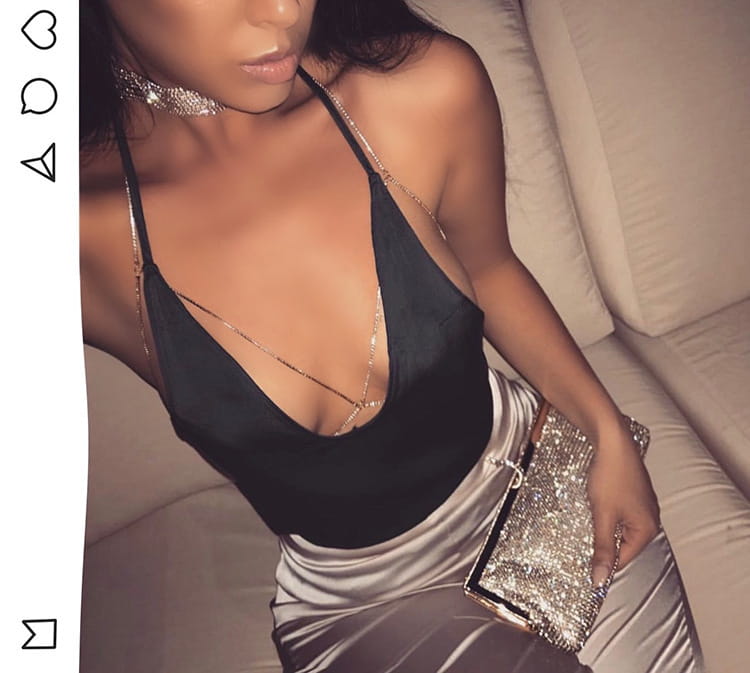 shiny black satin halter top with delicate gold chain straps and a plunging neckline paired with rhinestone body jewelry necklace for elegant evening wear