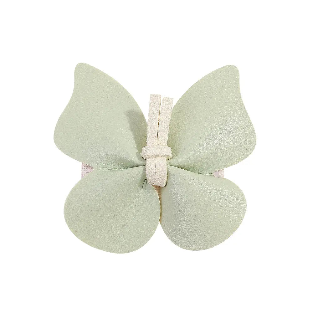 a delicate mint green leather butterfly bag clip children’s wristband featuring textured leather and a white lace-like tie at its center