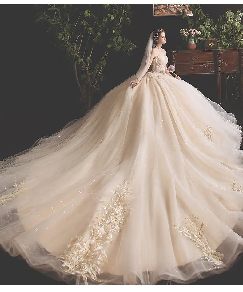 A flowing ivory bride summer tube gown in mori style trailing skirt design with intricate gold floral embroidery and a sheer veil.