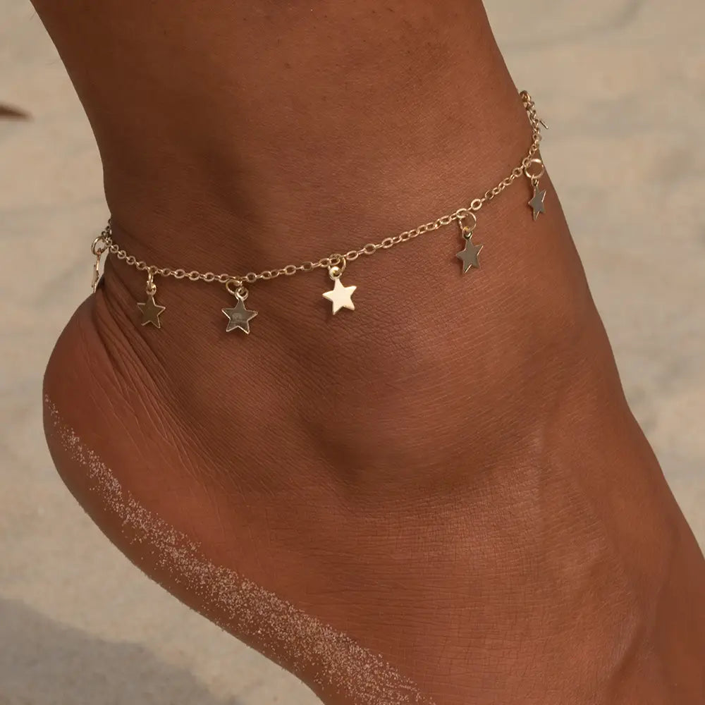Delicate gold-toned ankle chain with five dangling star charms designed as simple star fashion anklet ideal for fashion anklet jewelry.