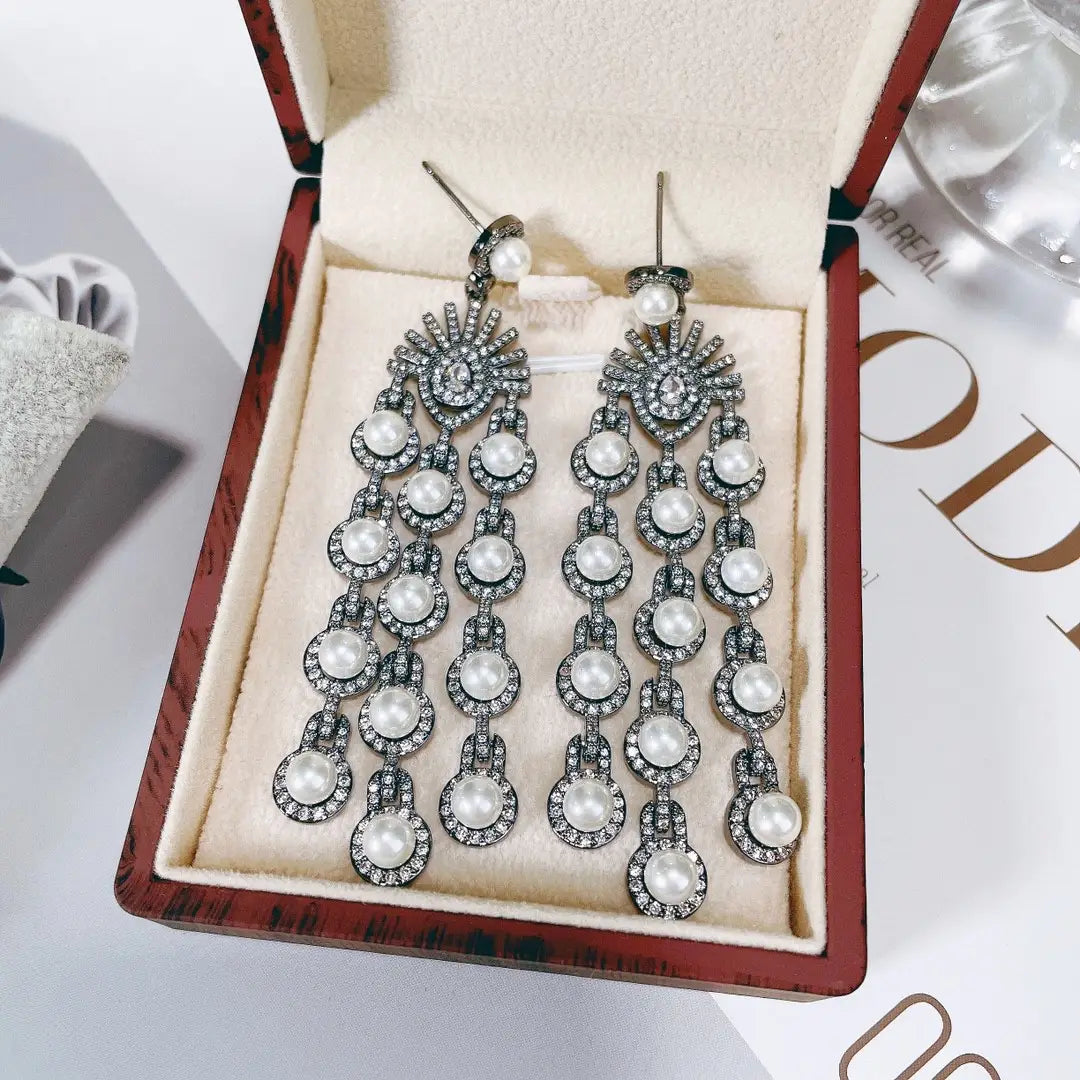 Elegant silver-toned silver pearl micro inlay zircon style beaded fringe earrings with cascading rows of round white pearls and sparkling rhinestones displayed in a luxurious red velvet-lined box.