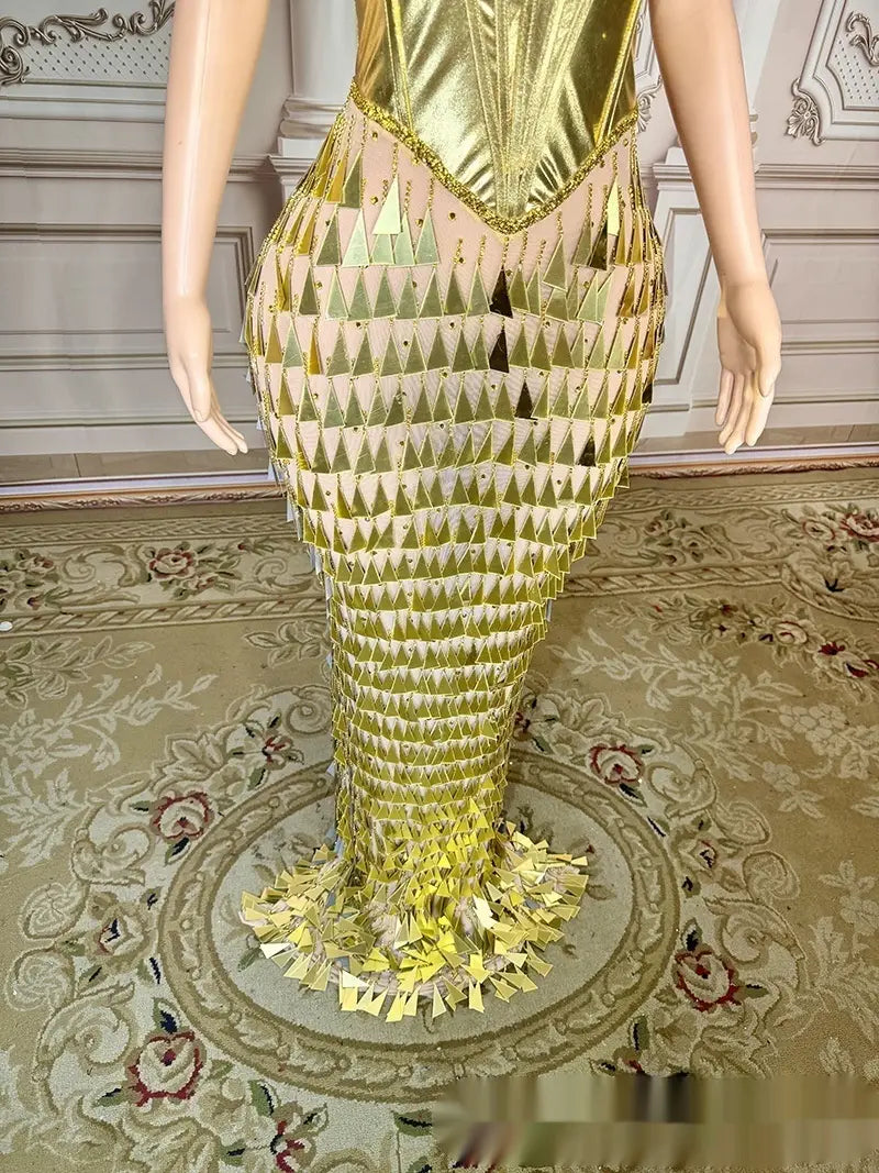 A shimmering gold mermaid-style gown featuring a fitted corset top and triangular sequins in a golden bright surface bandage metallic design.