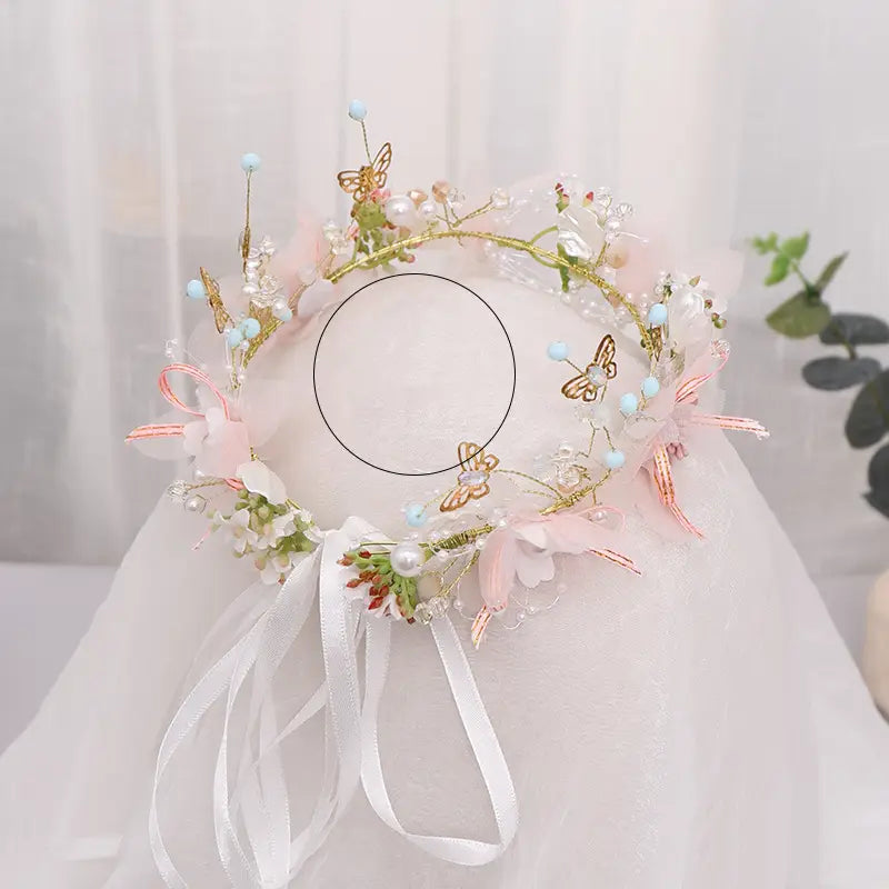A delicate pink and gold luxury floral bridal wreath adorned with butterflies, pearls, and sheer ribbons for elegant women’s fashion.