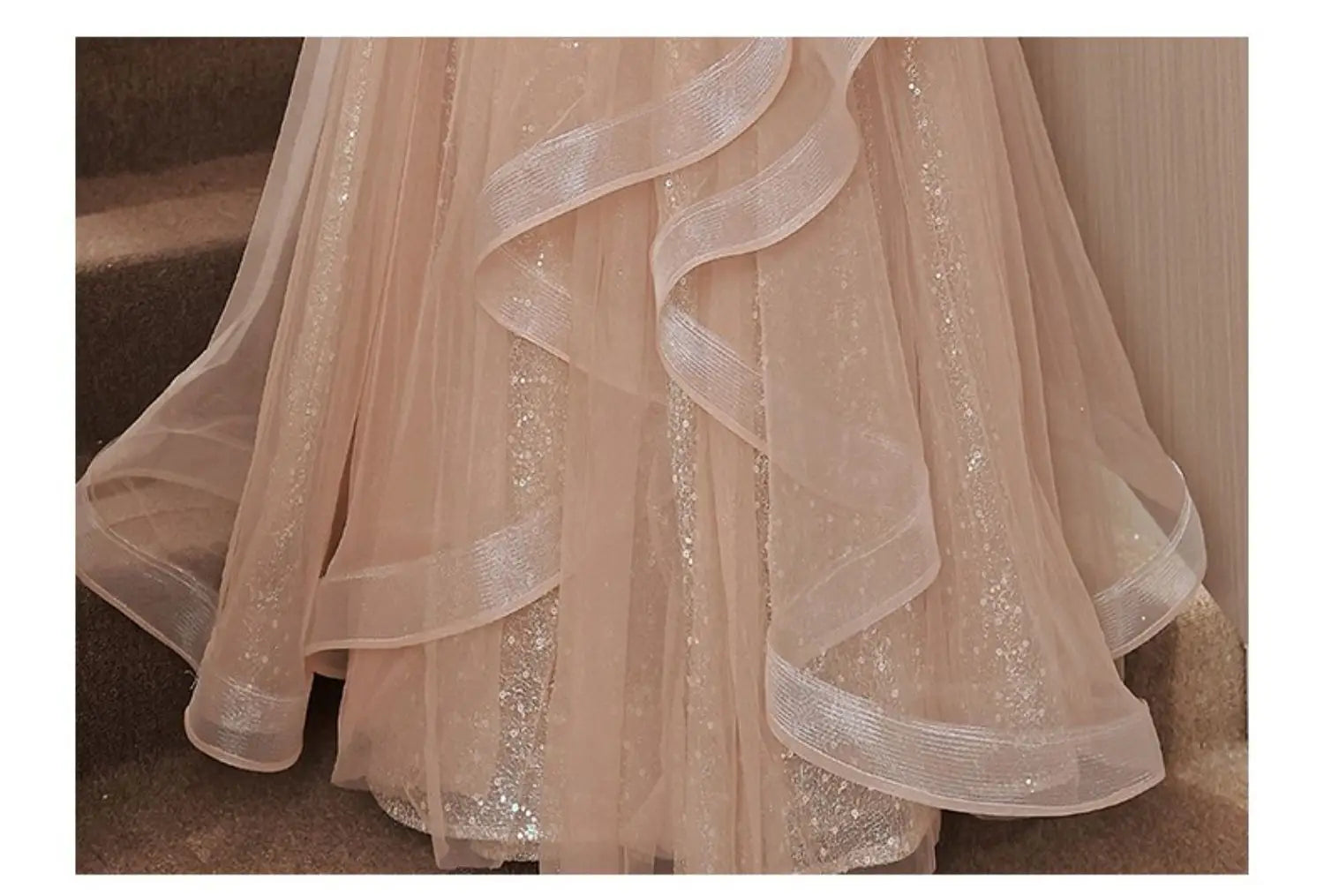 A delicate blush pink tulle luxury evening dress with shimmering silver sequin accents and layered ruffled ribbons.