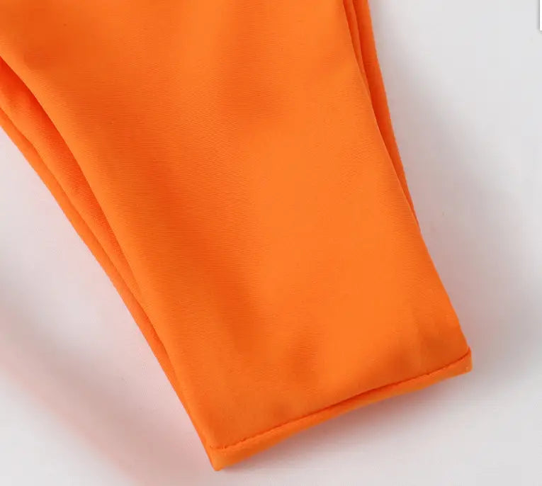 bright orange leggings made of smooth stretchy fabric complementing the orange crisscross split bikini set