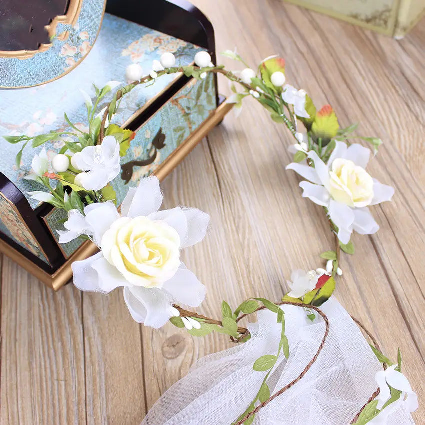 Handmade white rose bridal veil featuring a delicate white floral headpiece with artificial roses green leaves and small berries on a slender vine.