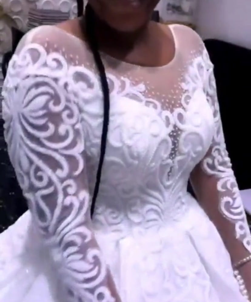 A white lace wedding gown plus size with intricate floral embroidery and sheer long sleeves featuring a plus size illusion design.