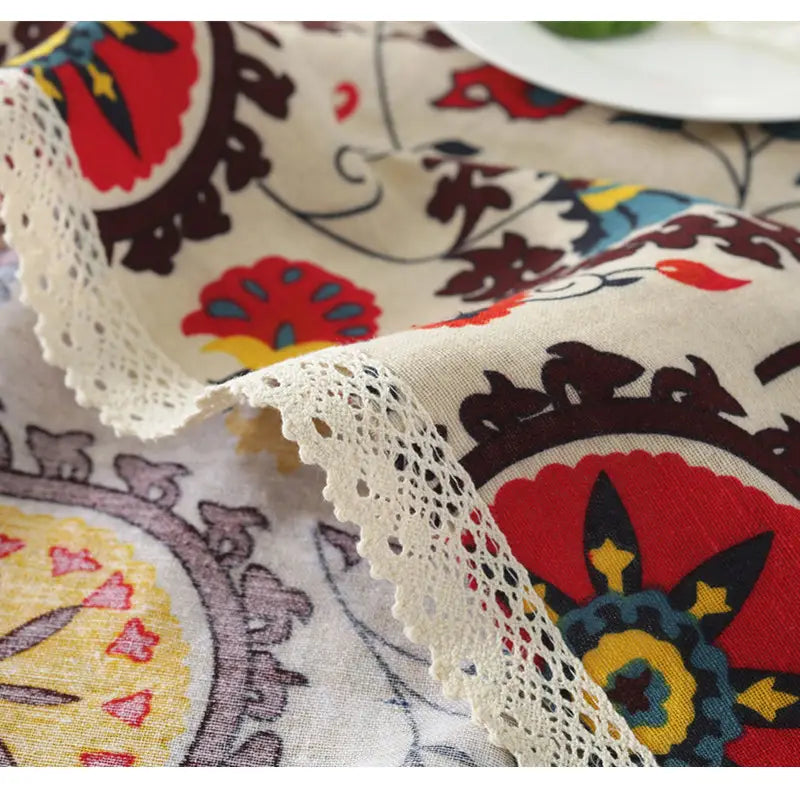 beige linen table cloth featuring vibrant red brown and yellow sunflower cotton floral patterns edged with delicate white lace trim