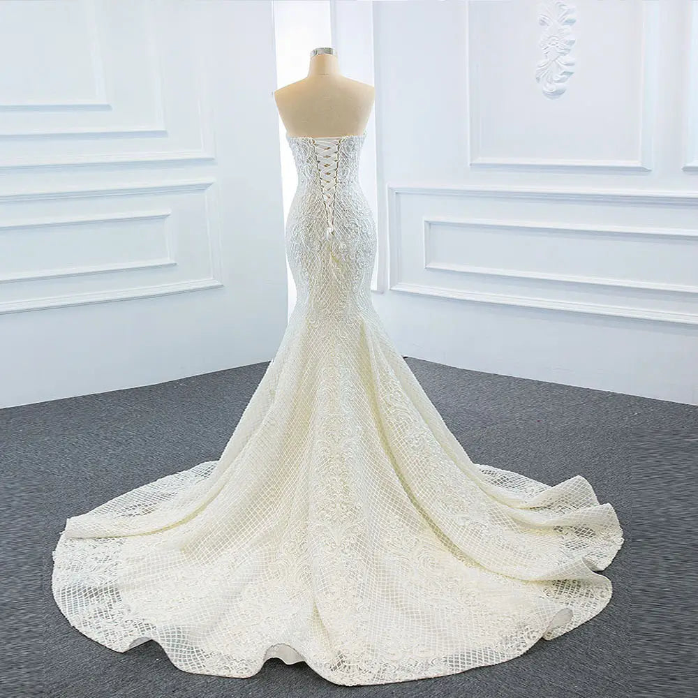 A white lace mermaid wedding dress wears two fishtail train with a fitted bodice and an elaborate back train.
