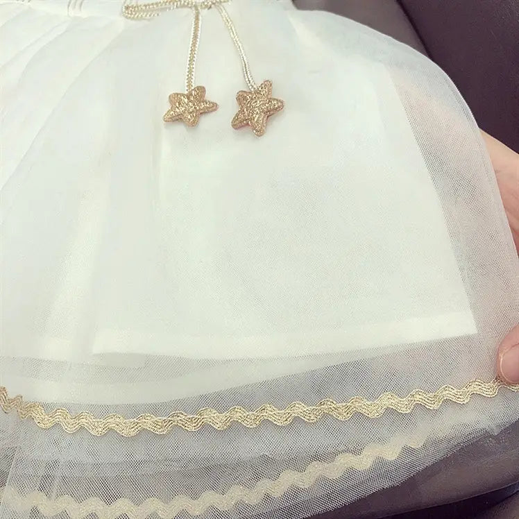 A delicate white baby gauze princess dress featuring gold star-shaped charms and scalloped lace trim ideal as a gauze dress summer outfit.