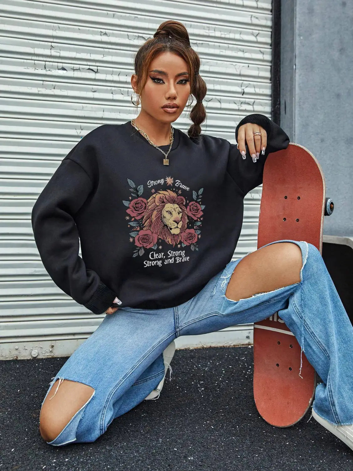 black oversized regular fit long sleeve sweatshirt featuring a lion and rose graphic design with the text strong brave above and clear below