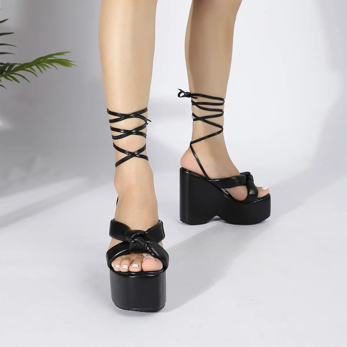 black platform wedge high heel sandals with crisscross ankle straps and a bow detail on the toe in a high heel platform design