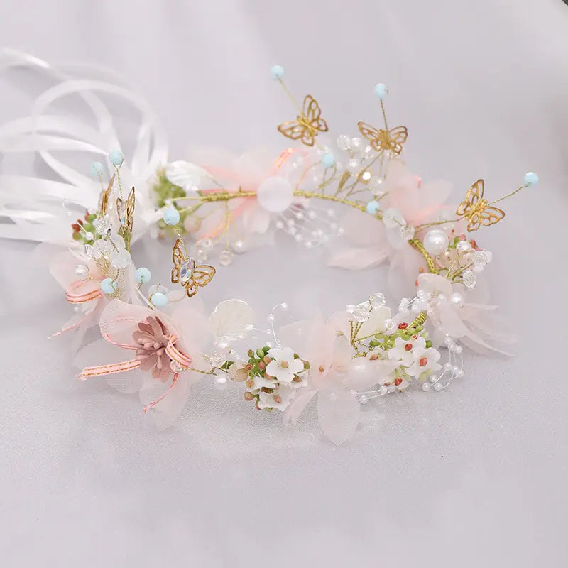 Luxury floral bridal wreath featuring a delicate headband adorned with sheer pink and white fabric flowers, gold butterfly accents, pearls, and light blue beads, perfect for luxury women’s fashion occasions.