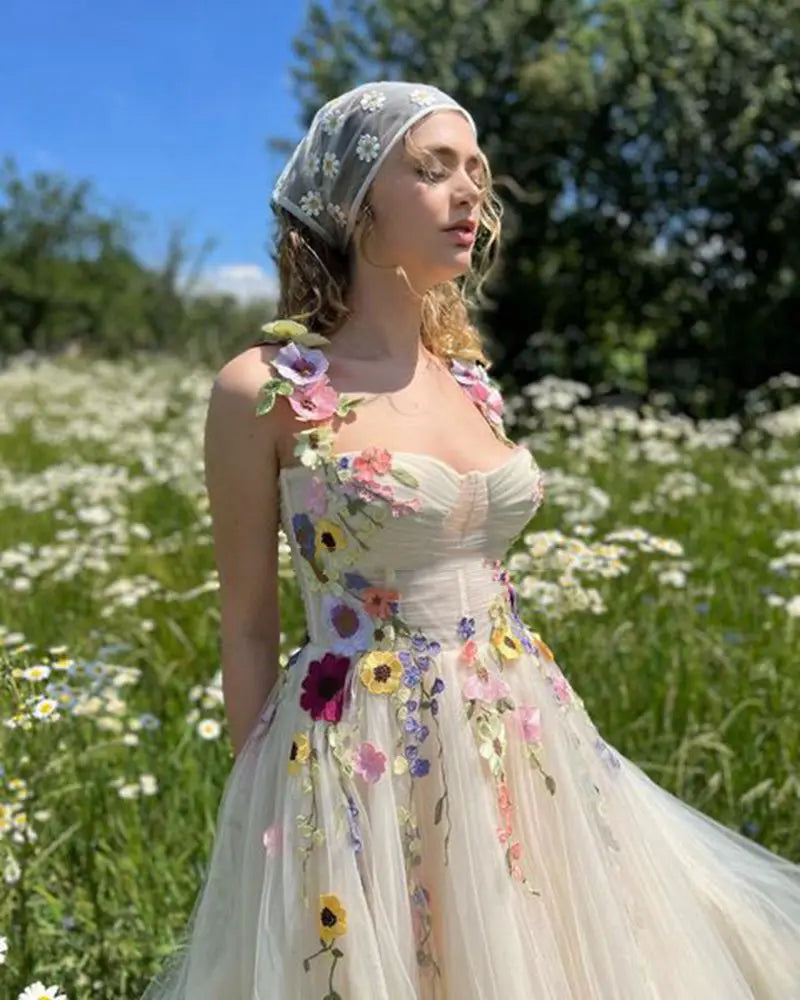 a delicate off-white floral gown featuring vibrant hand-embroidered flowers in shades of pink purple yellow and blue made of light champagne tulle for a tulle prom dress look