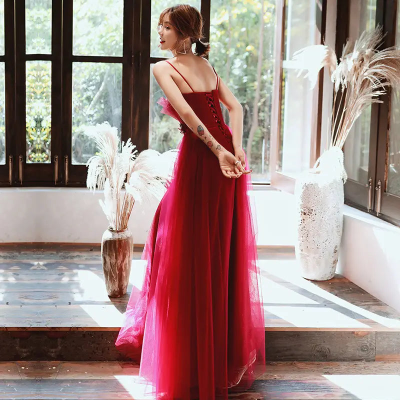 A flowing deep red satin evening dress with thin engagement suspender straps and a lace-up back, ideal for formal wear engagement suspender events.