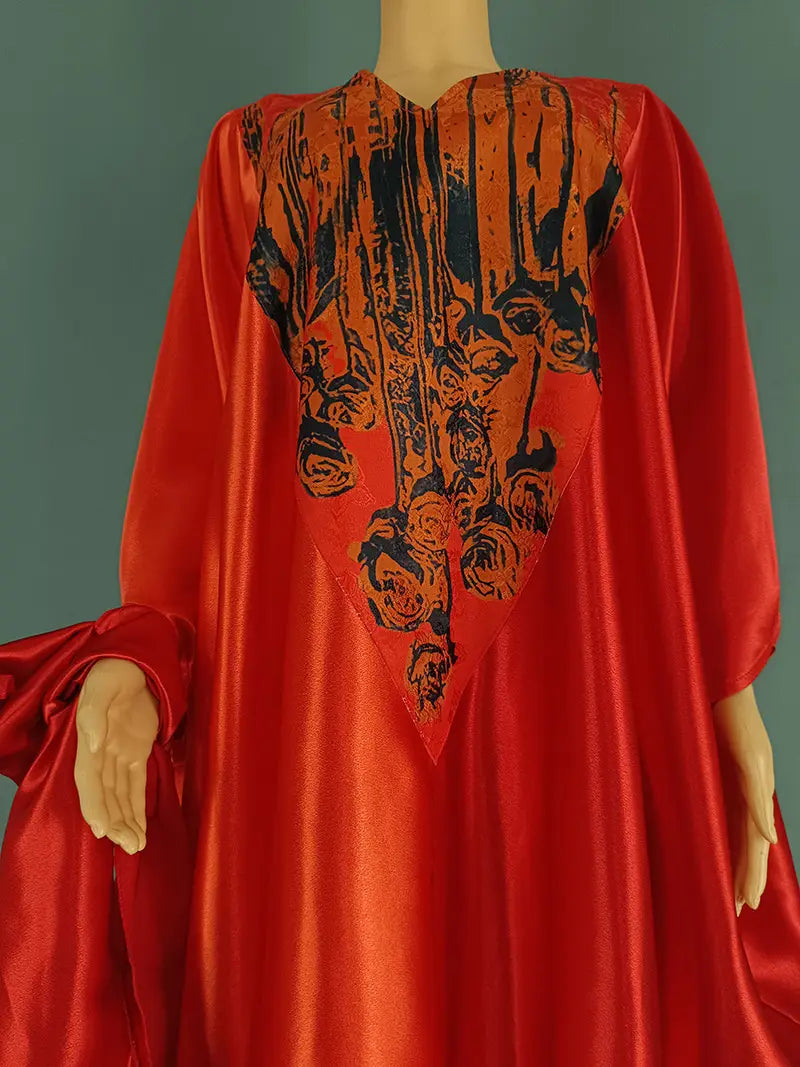 Vibrant red satin kaftan featuring a bold black and orange abstract face pattern across the bodice.