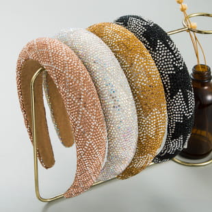 A collection of five sparkling beaded baroque vintage court style crystal headbands in rose gold white mustard yellow black with silver dots and shimmering peach hues.