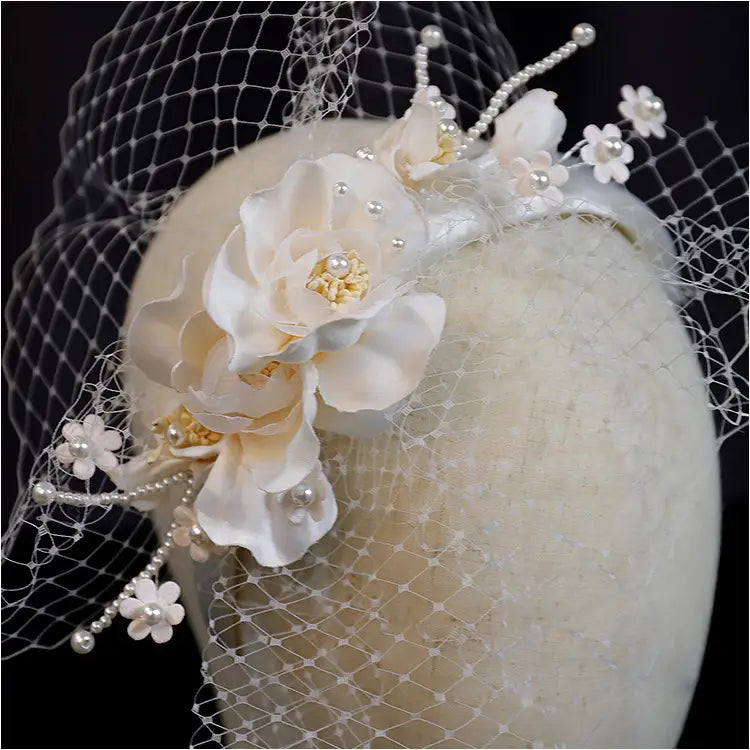 Elegant ivory petal mesh hairband featuring fabric flowers, pearl accents, and a sheer veil in a delicate lace design.