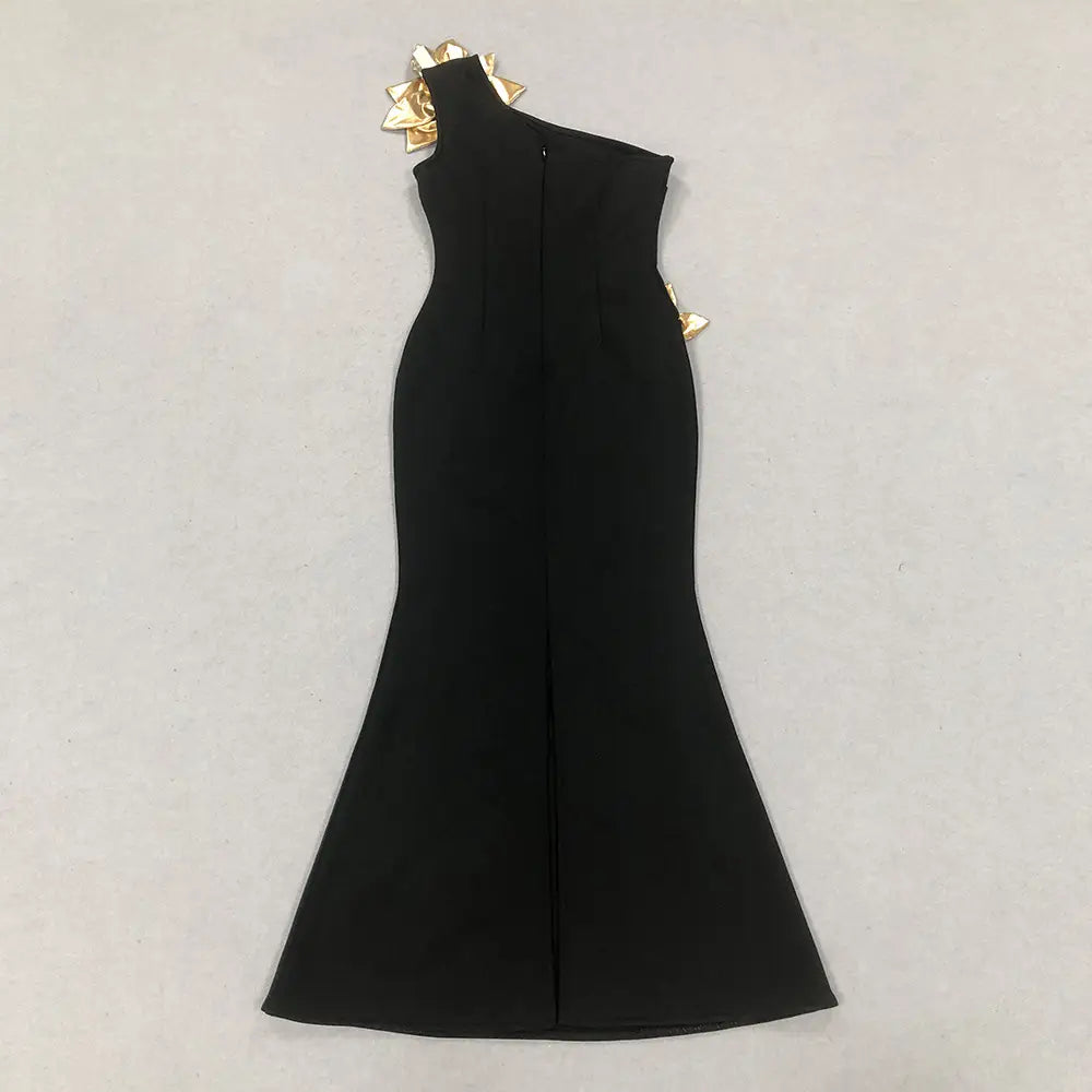 Black satin bandage golden flower maxi dress featuring a one-shoulder mermaid gown design with gold geometric embellishments at the shoulder.