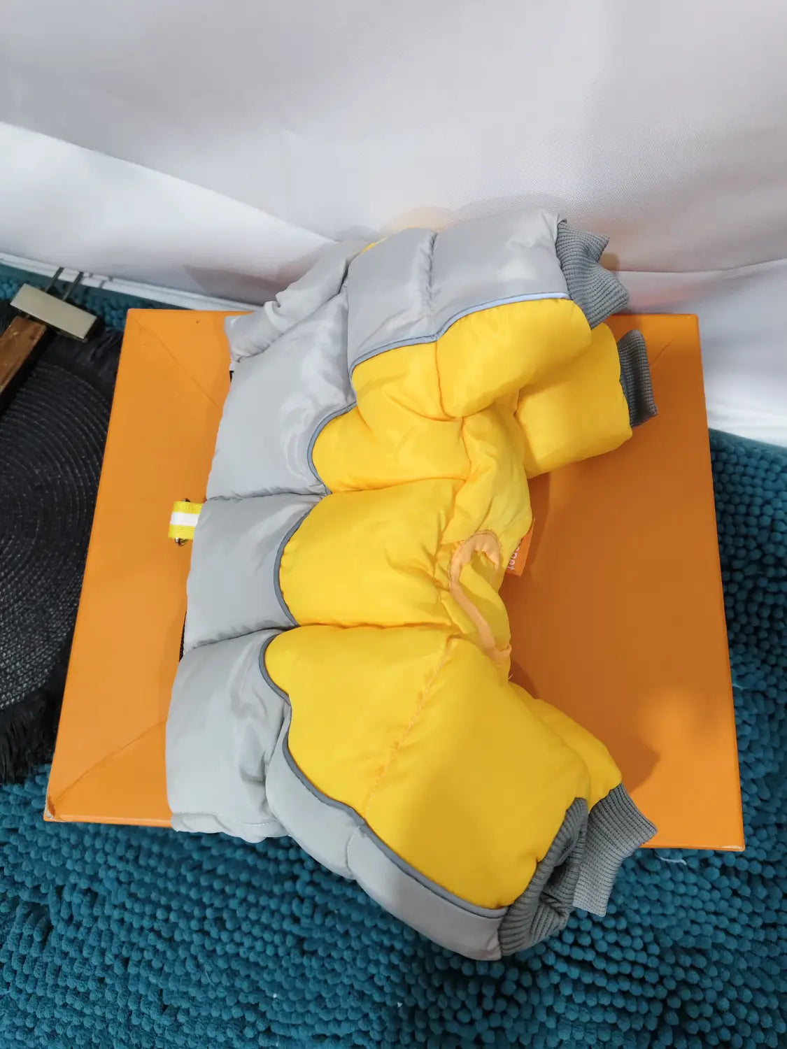 a puffy two-tone yellow and gray children’s winter jacket with ribbed cuffs displayed as dog winter clothes for pet dog use
