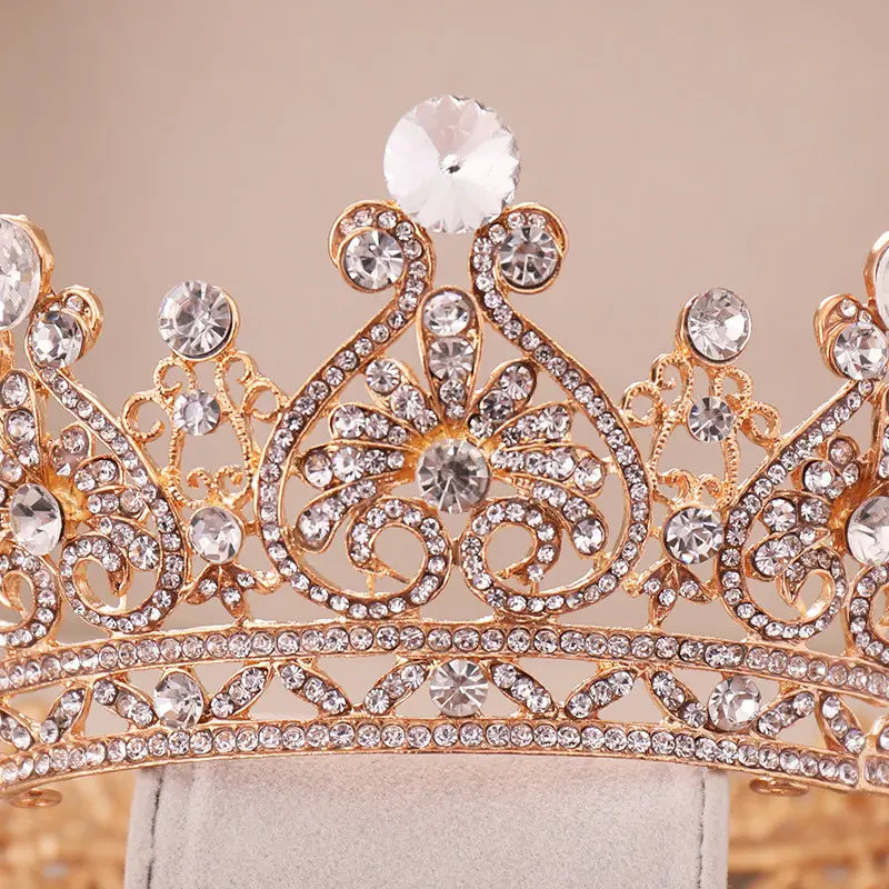 A sparkling rose gold rhinestone big european princess crown hair tiara featuring intricate gold filigree and clear crystals with a central diamond in an ornate floral design.