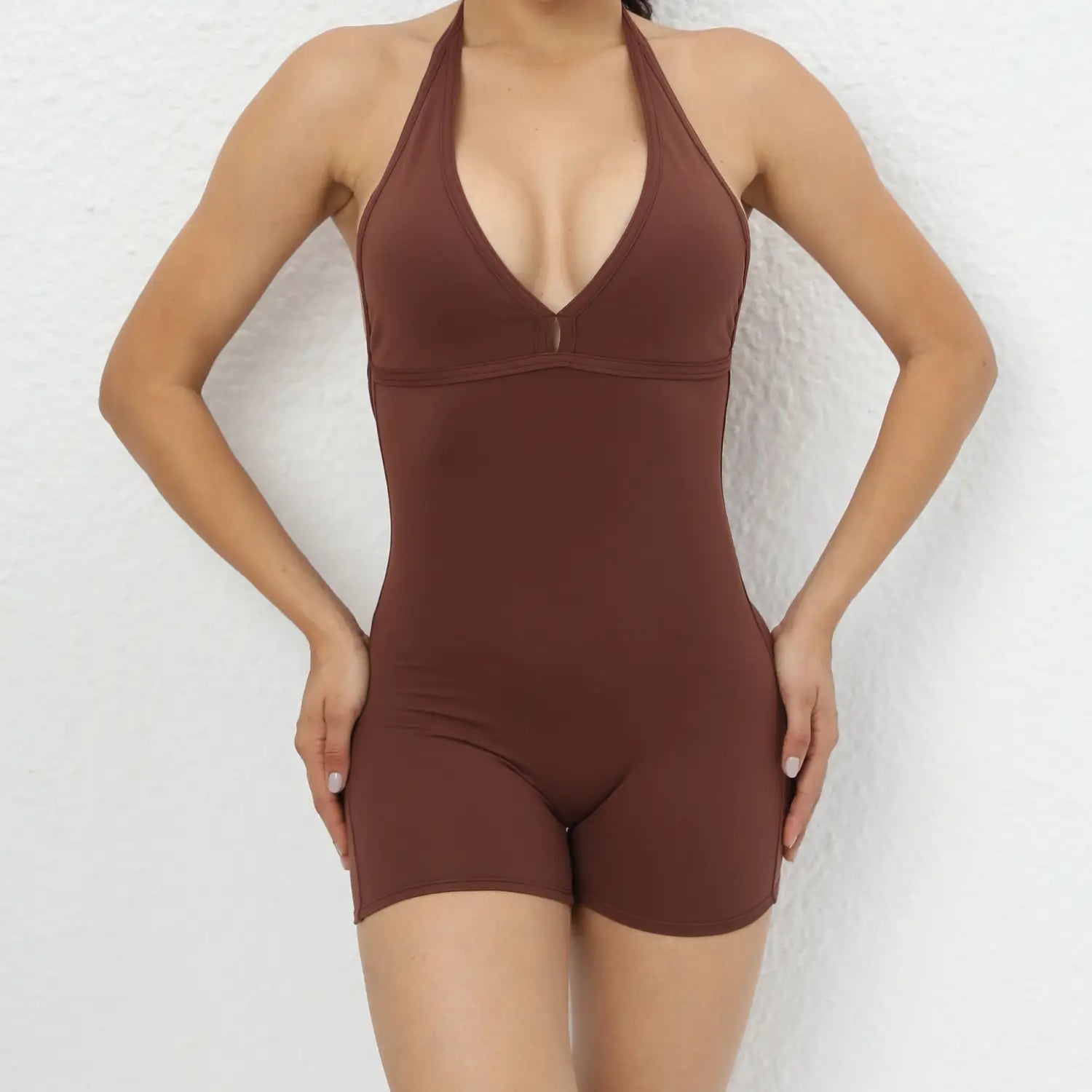 A sleek chocolate-brown halter neck one-piece yoga romper with high elastic fabric and a deep v-cut neckline designed for a form-fitting silhouette.