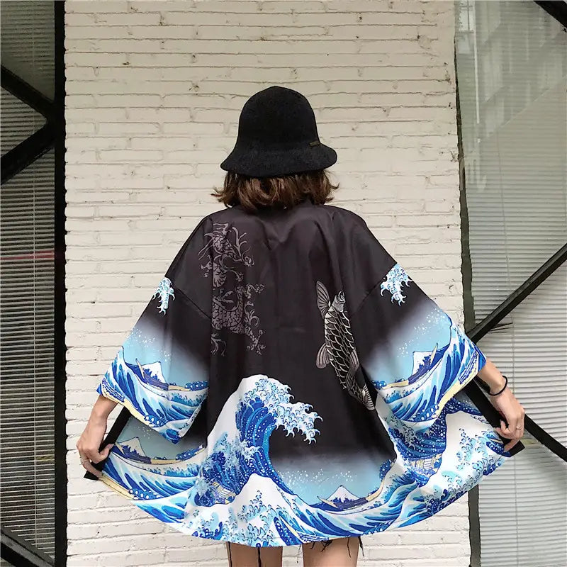 black kimono style coat featuring a vibrant blue and white wave pattern inspired by Hokusai the great wave off Kanagawa with detailed fish and mountain motifs designed as sun protection clothing