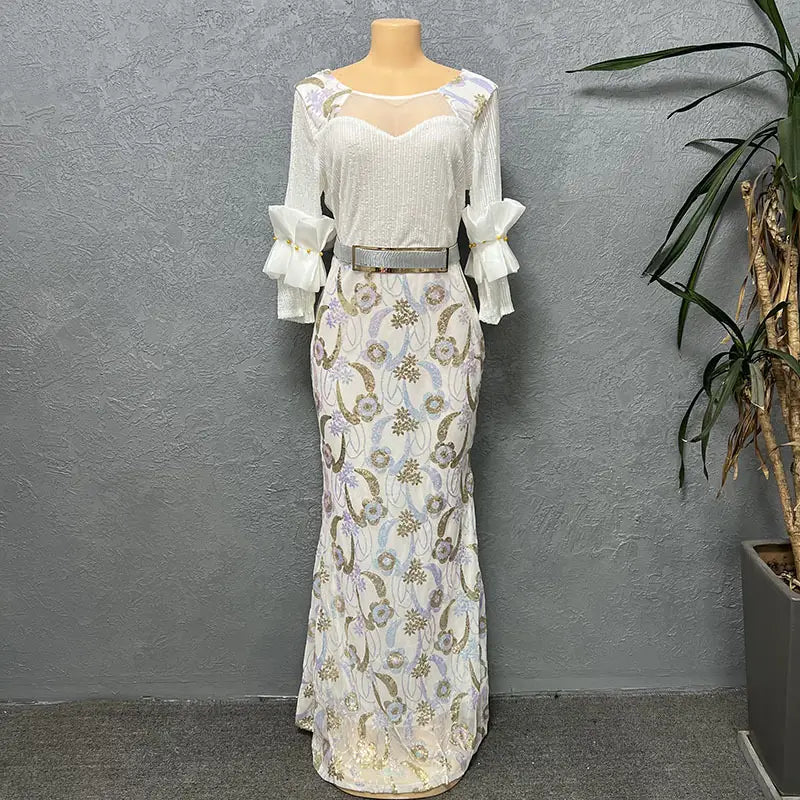 Elegant white mermaid-style half sleeve slim evening dress with intricate gold and lavender floral embroidery, sheer illusion round neck shirt, ruffled sleeves, and metallic belt.