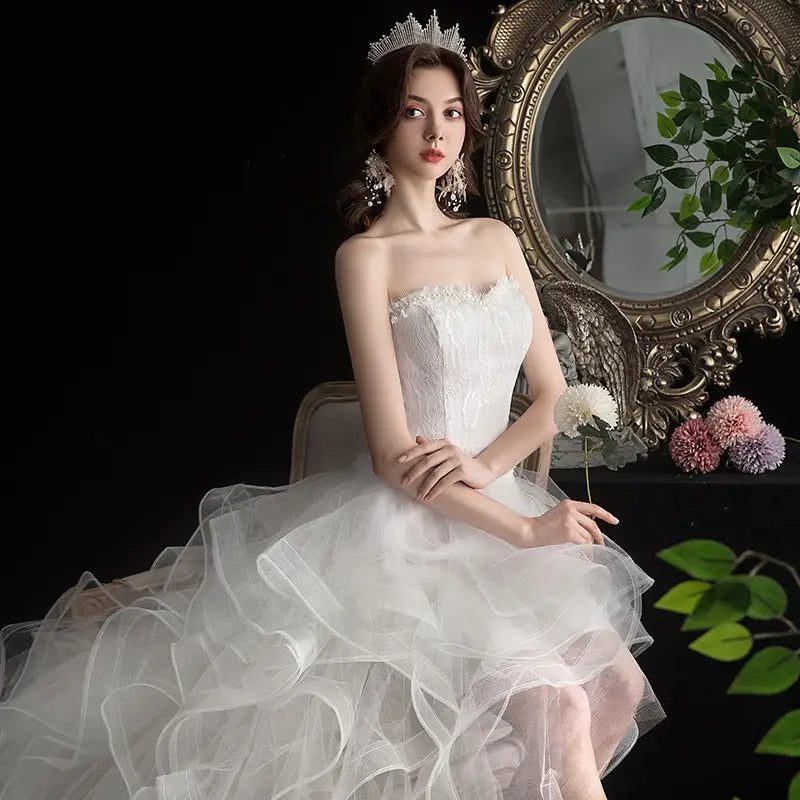 a strapless white lace wedding dress featuring a fitted bodice and a voluminous layered tulle skirt, designed as a small trailing wedding dress with length small trailing details.