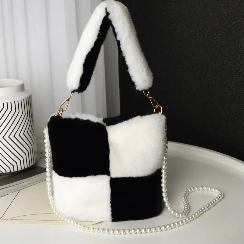 A black and white checkered plush bucket bag made of faux fur featuring a pearl chain design strap.