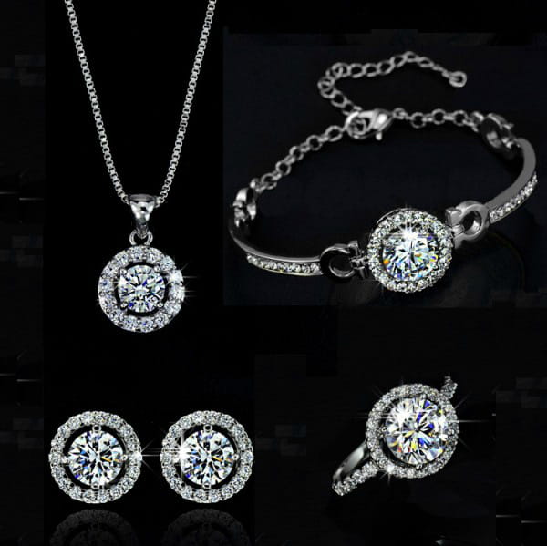 Silver-toned diamond-set jewelry sets featuring a necklace bracelet earrings and ring with sparkling clear stones encircled by smaller crystals for luxury women’s fashion.