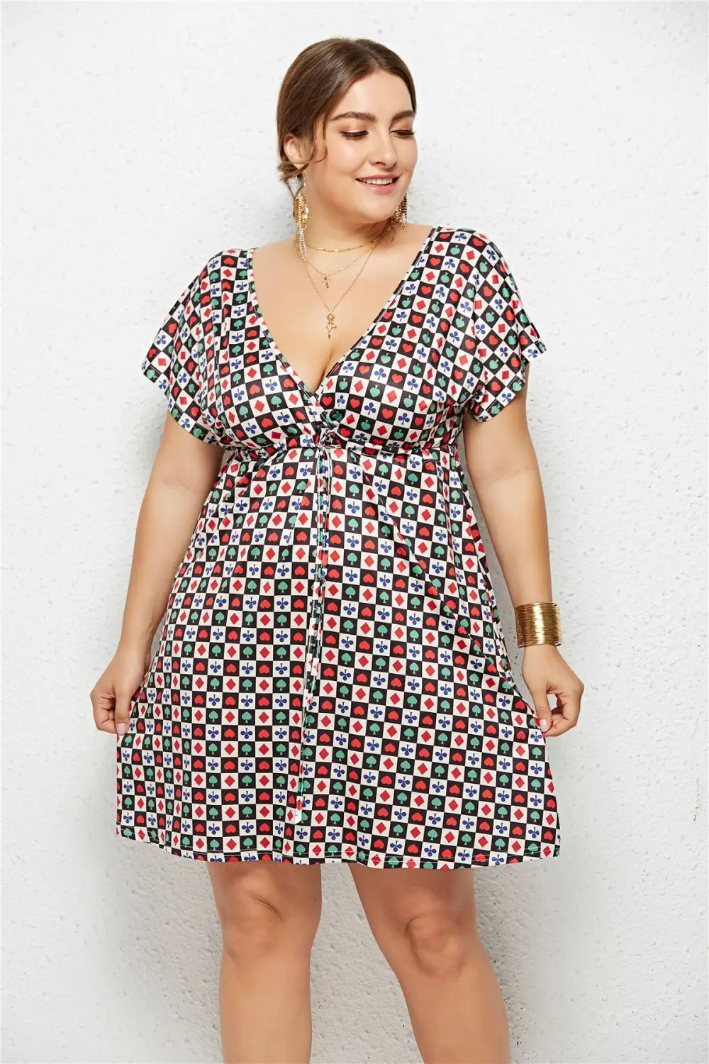 a plus-size woman wearing a vibrant geometric printed deep v-neck dress with a short sleeve design and an elastic waist tied with a matching belt