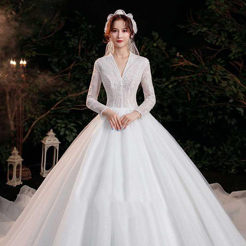 Elegant white wedding gown with intricate lace detailing on the bodice and temperament trailing long sleeves featuring a voluminous tulle skirt.