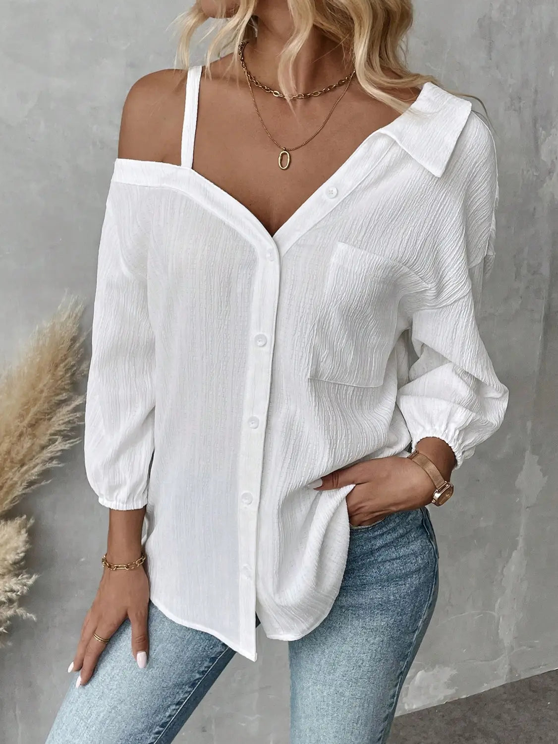 white asymmetric off shoulder blouse in solid color white featuring a lightweight textured fabric with subtle pleats and button-down design