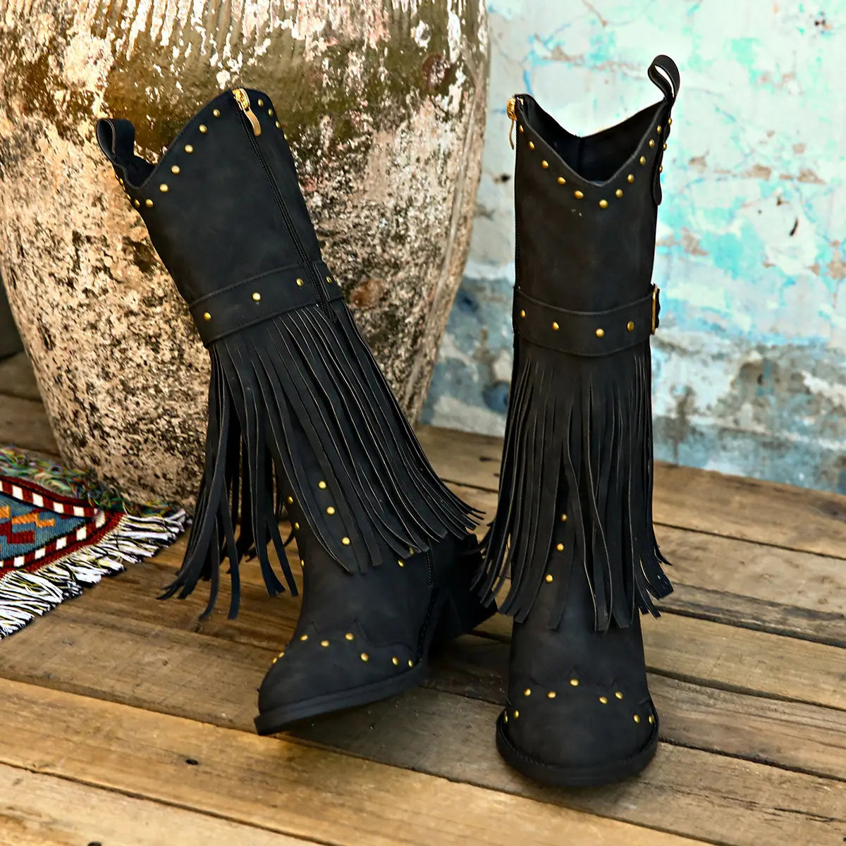 Black suede cowboy boots with gold-tone studs and fringe detailing featuring a fashion square heel perfect for retro winter fashion.