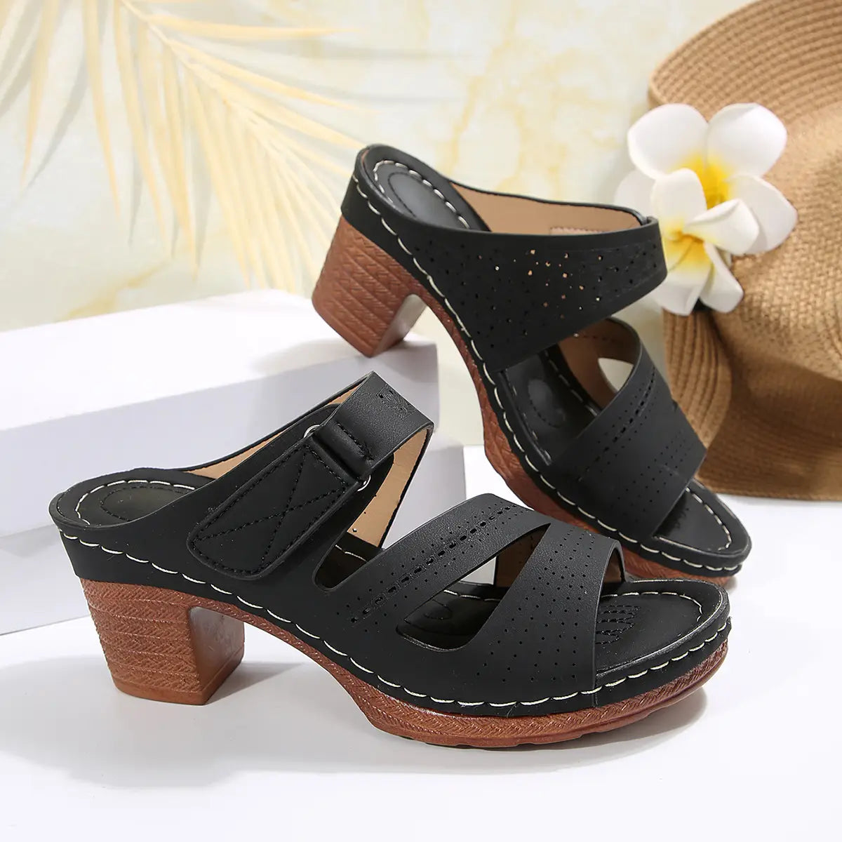 black perforated leather mule sandals with white stitching and a brown textured block heel designed as summer casual chunky shoes perfect for slides shoes summer.