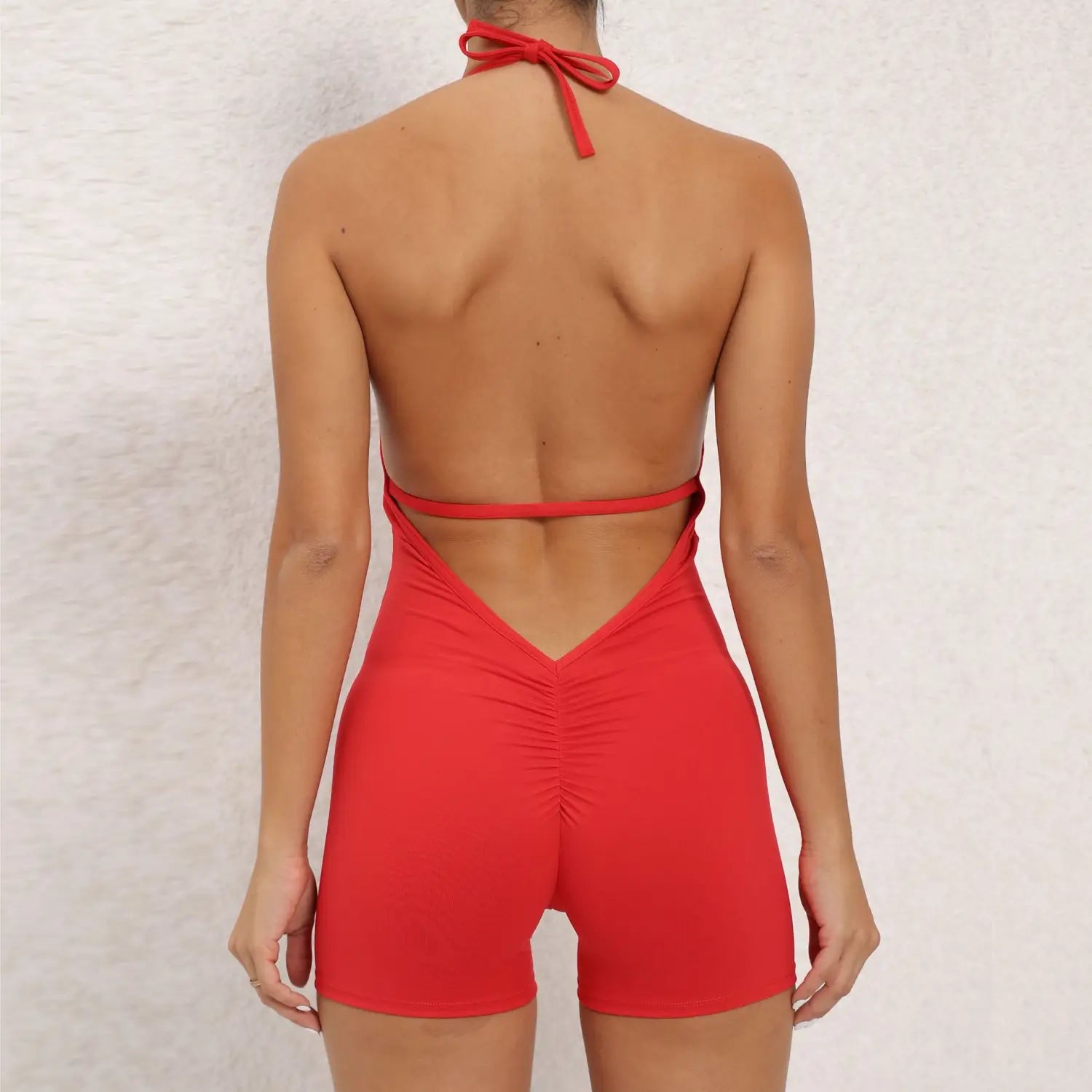 red halter neck high elastic yoga romper with a back tie and ruched detailing in a one-piece swimsuit style