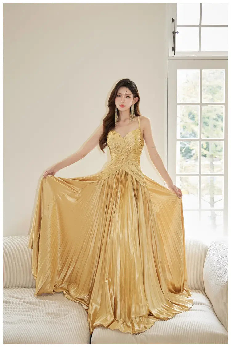 A shimmering gold satin heavy industry birthday dress with a fitted bodice and a flowing pleated skirt.