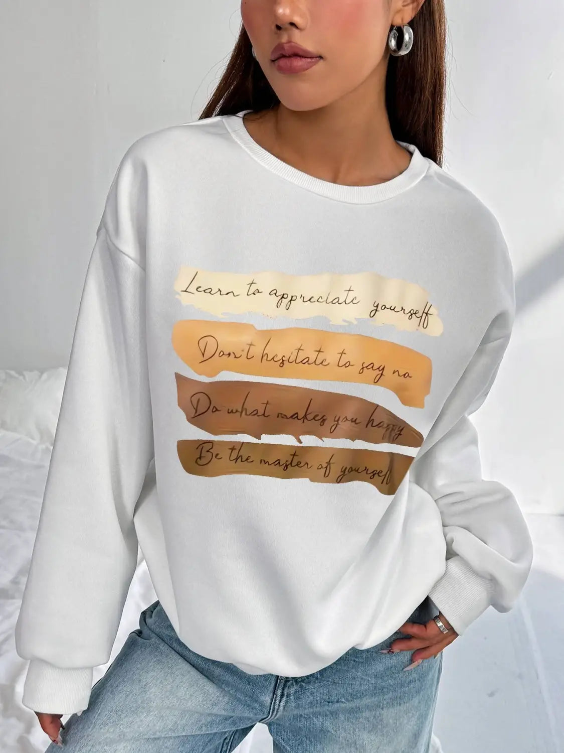 White oversized long sleeve sweatshirt in solid colour featuring a motivational quote printed in brown and beige tones ideal for daily wear.